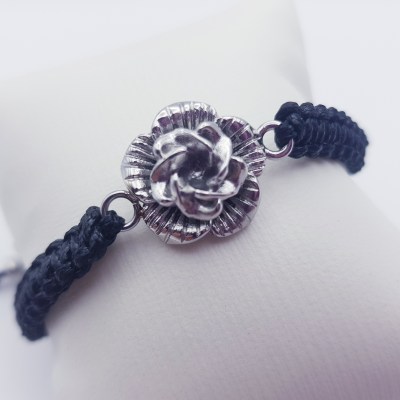 Aschesarmband mit einer silbernen Blume und einem schwarzen Lederband.